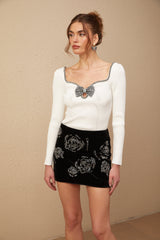 A black velvet mini skirt covered in shimmering sequins hanging on a display