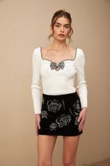 A black velvet mini skirt with sequin embellishments shimmering in the light