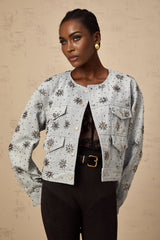 A blue denim jacket with studded sun motifs and decorative embellishments featuring a distressed look and visible stitching details