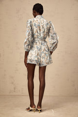 A blue floral print jumpsuit with lace trim and ruffled details featuring a feminine Eugenie style design