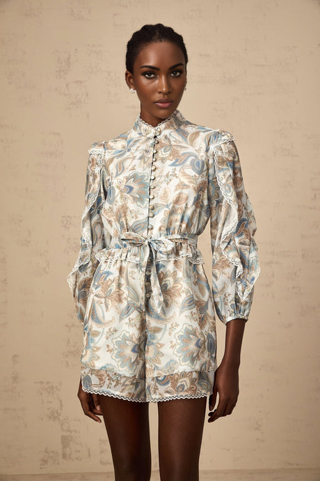 A blue floral print jumpsuit with lace trim and ruffled details named Eugenie