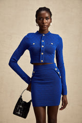 A blue knitted matching set consisting of a top and skirt The top features button details and both pieces have a coordinated design