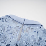 A blue midi dress with floral lace appliques and a delicate floral pattern throughout the fabric
