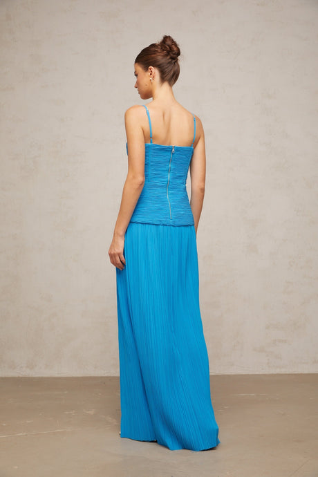 A blue pleated maxi dress with side slits and a flowing silhouette