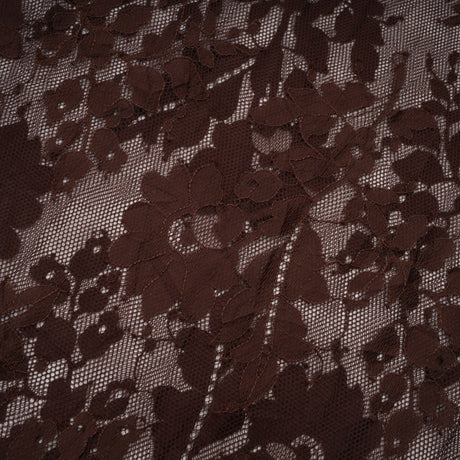 A brown flared midi dress made of chantilly lace named Sylvie hanging on a hanger against a plain background