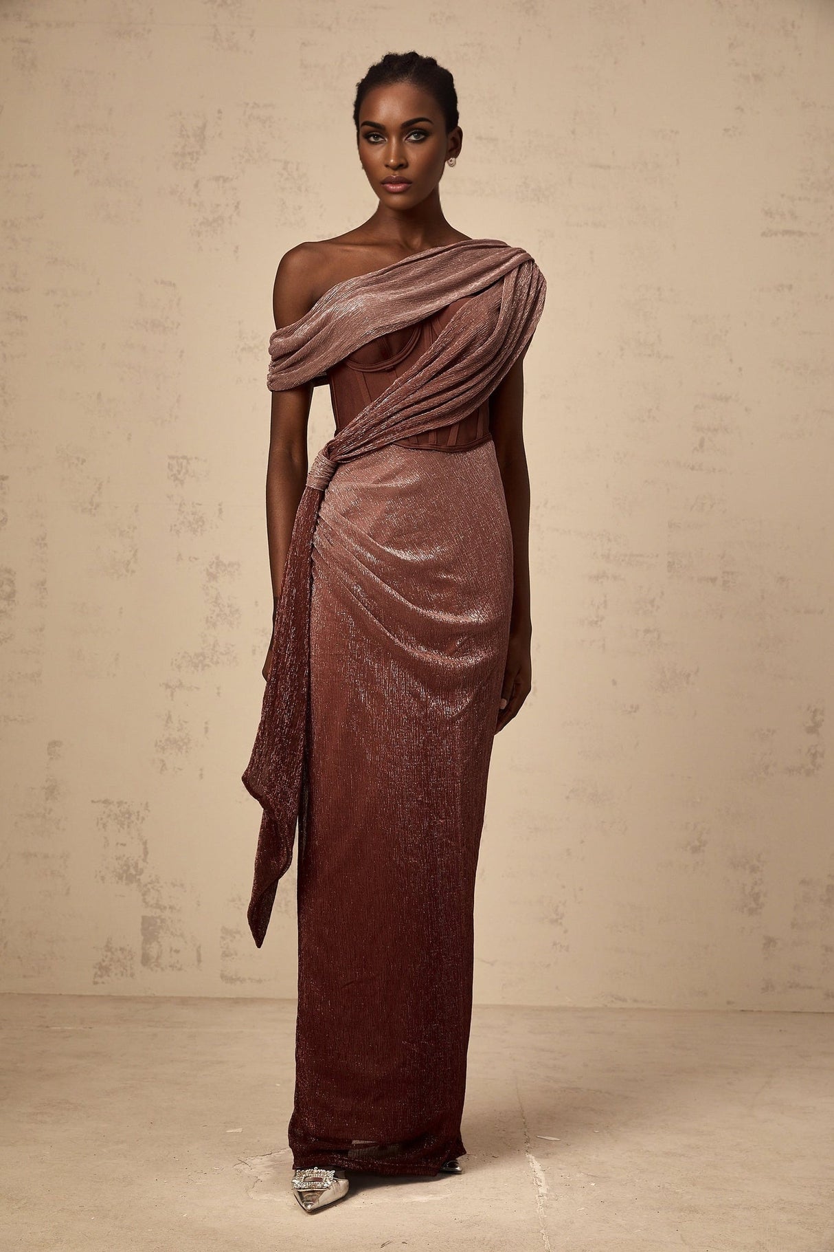 A brown maxi dress with a corsetstyle bodice featuring ribbon detailing and a long flowing skirt