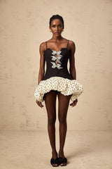 A colorful mini dress with a bow accent featuring a color block design and polka dot pattern