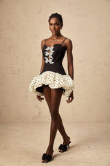 A colorful mini dress with polka dot pattern featuring a color block design and a decorative bow detail