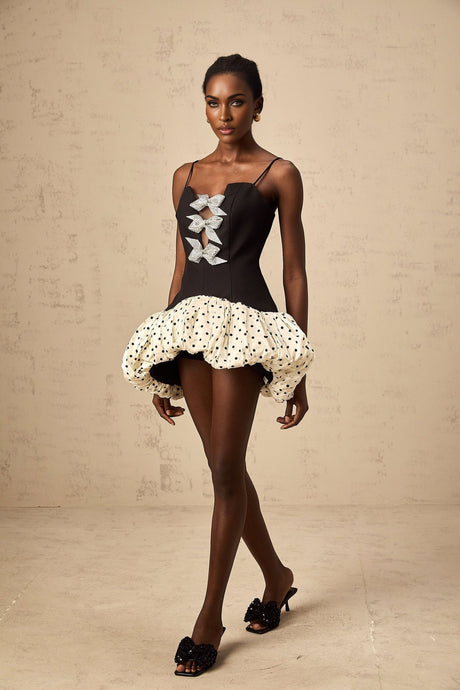 A colorful mini dress with polka dot pattern featuring a color block design and a decorative bow detail