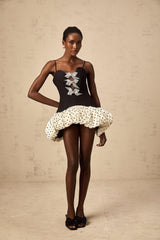 A colorful mini dress with polka dots featuring a color block design and a decorative bow detail