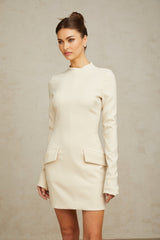 A creamwhite fitted mini dress by Chloé hanging on a clothing rack against a plain background
