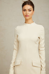 A creamwhite fitted mini dress by Chloé hanging on a plain background showcasing its sleek silhouette and elegant design