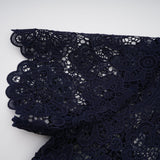 A dark blue midi dress with a floral crochet lace pattern covering the entire garment