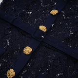A dark blue midi dress with a floral crochet lace pattern worn by a model standing against a plain background