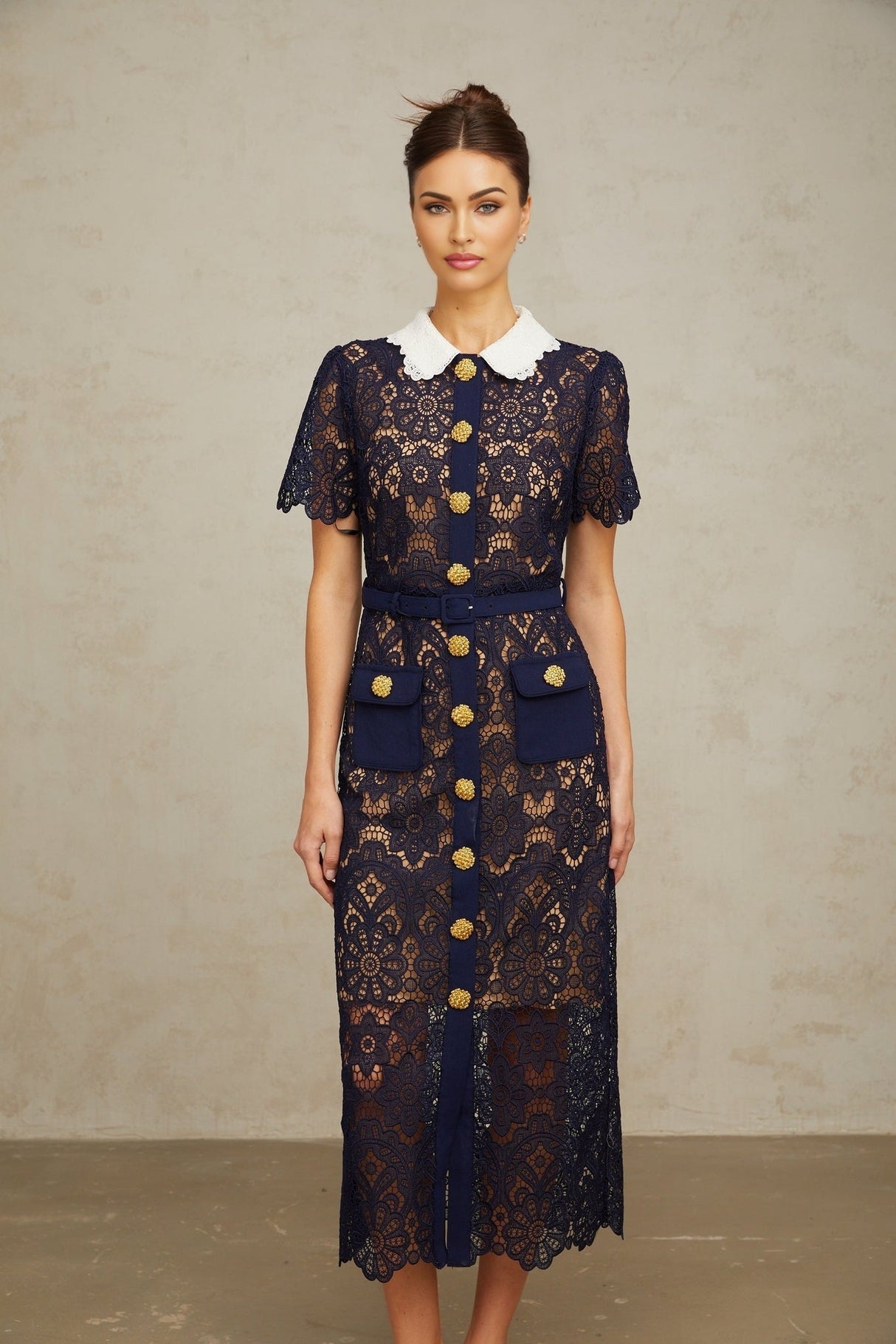 A dark blue midi dress with floral crochet lace detailing named Ariane