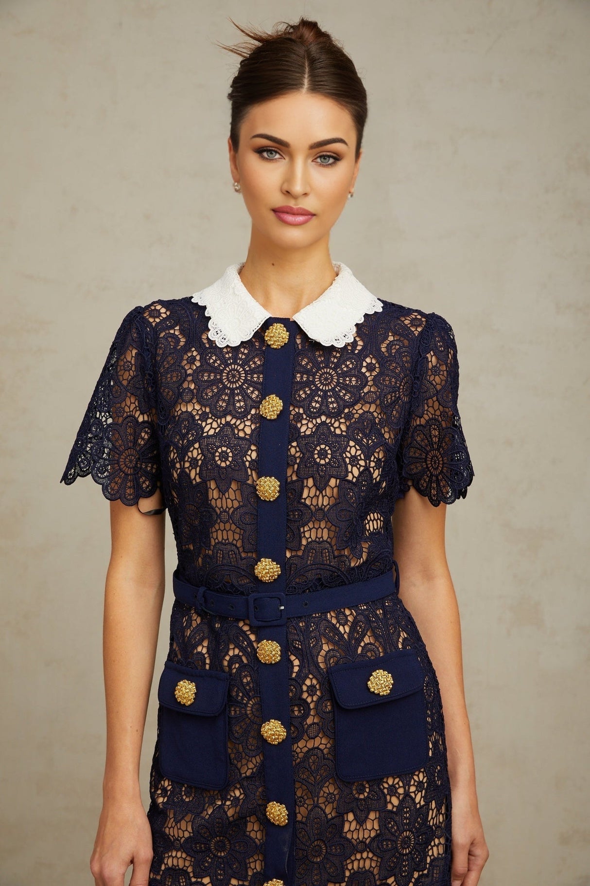 A dark blue midi dress with floral crochet lace pattern featuring an intricate design throughout the garment