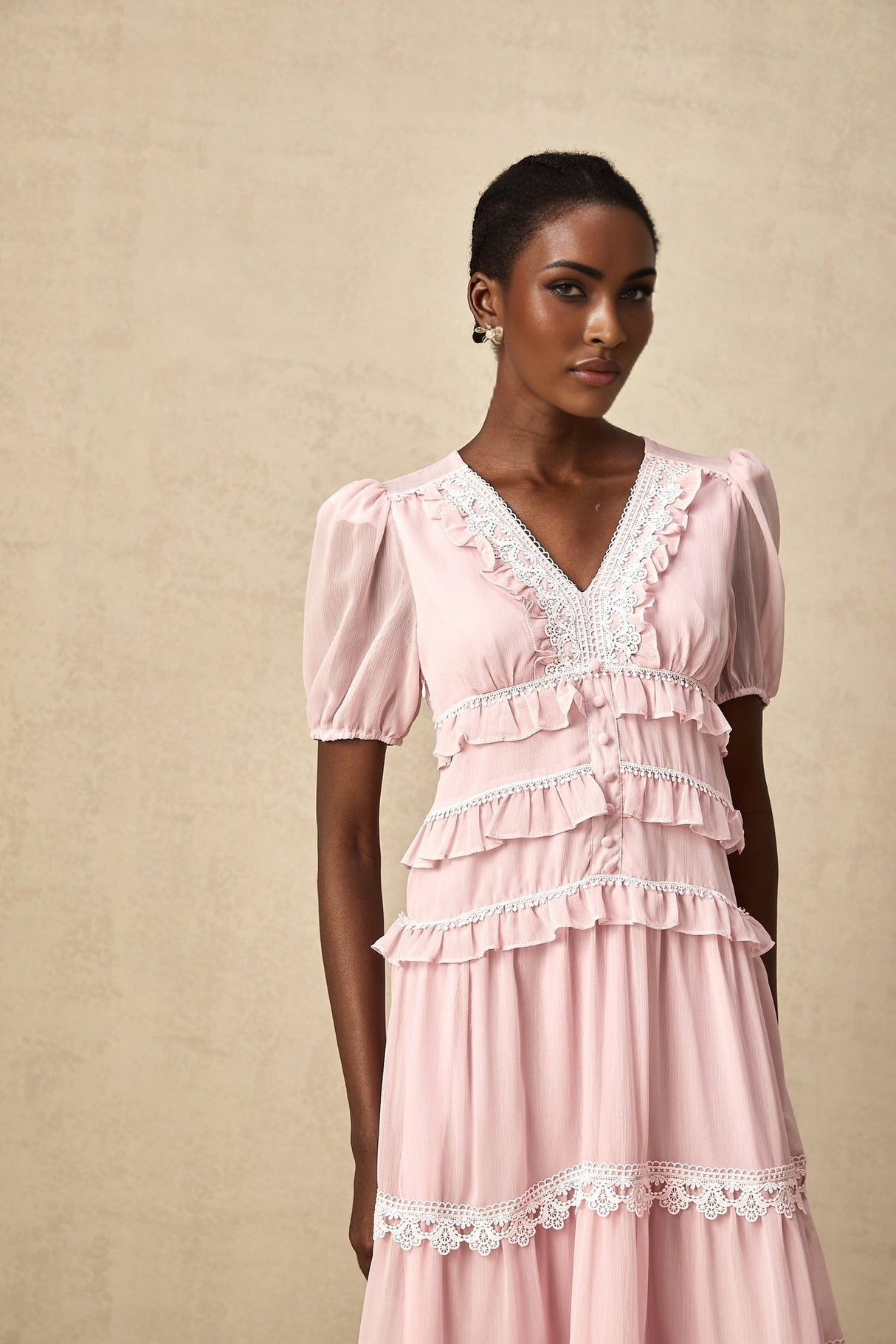 A feminine pink midi dress with ruffled tiers and a flowy silhouette named Amelie