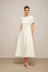 A flared midi dress in neutral colors featuring orange floral appliqués