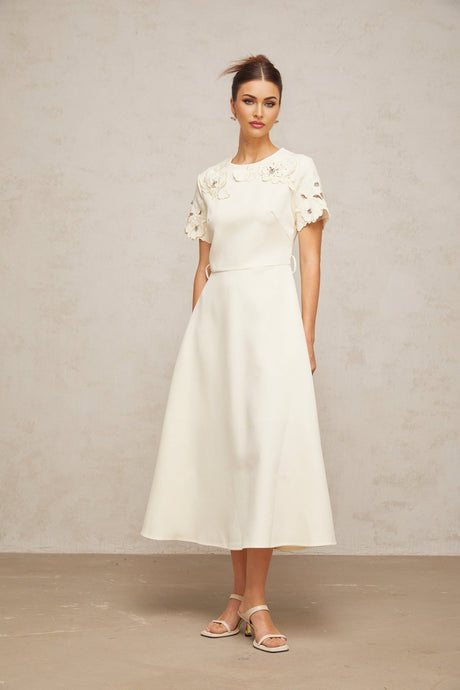 A flared midi dress in neutral colors featuring orange floral appliqués
