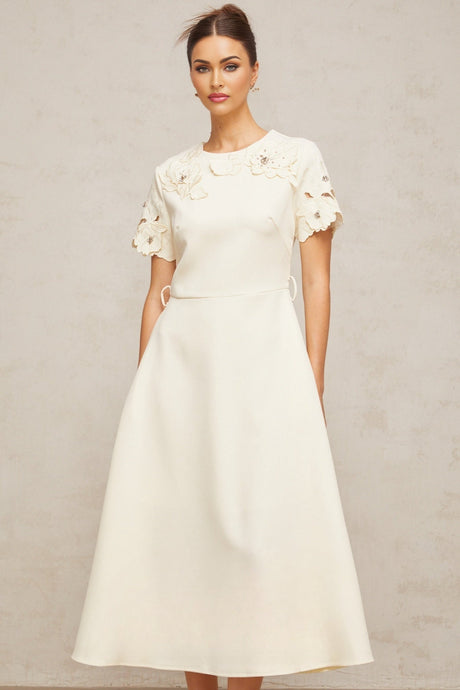A flared midi dress in neutral tones featuring orange floral appliqués on the fabric