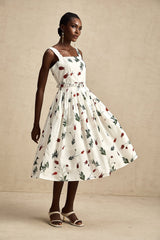 A floral print midi dress with a white background and colorful flower pattern featuring long sleeves and a flowy skirt