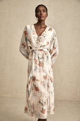A floral print midi dress with an open waist design featuring a colorful pattern on a light background The dress has a flowing silhouette and hits below the knee