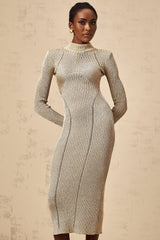 A gold colored ribbed knit midi dress with pointelle detailing worn by a model standing against a plain background
