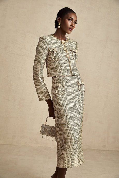 A gold colored tweed jacket and matching skirt set with sequin embellishments The outfit has a luxurious and festive appearance suitable for formal occasions