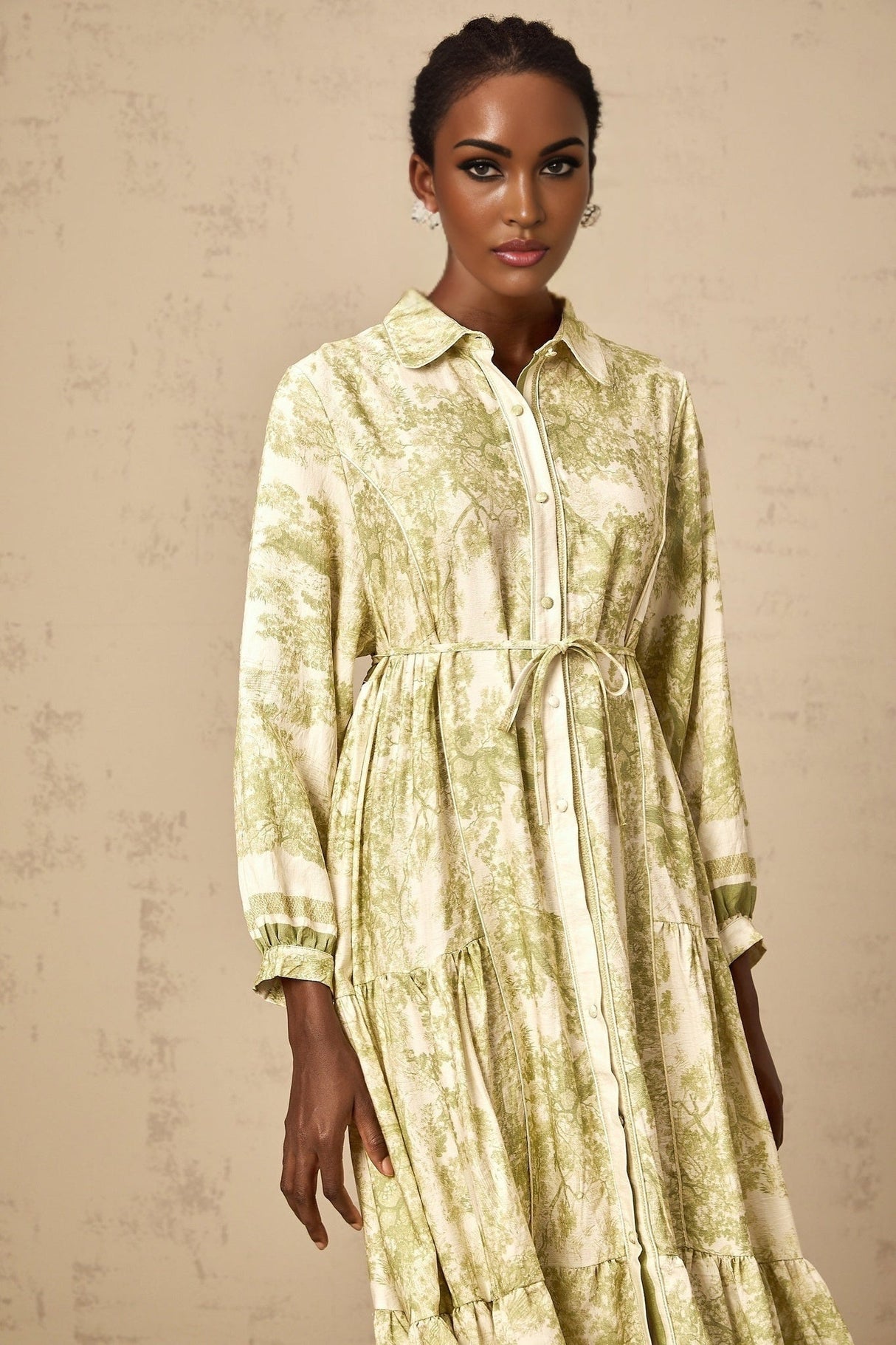 A green midi dress with a graphic print pattern featuring the Adélaïde design worn by a female model against a plain background