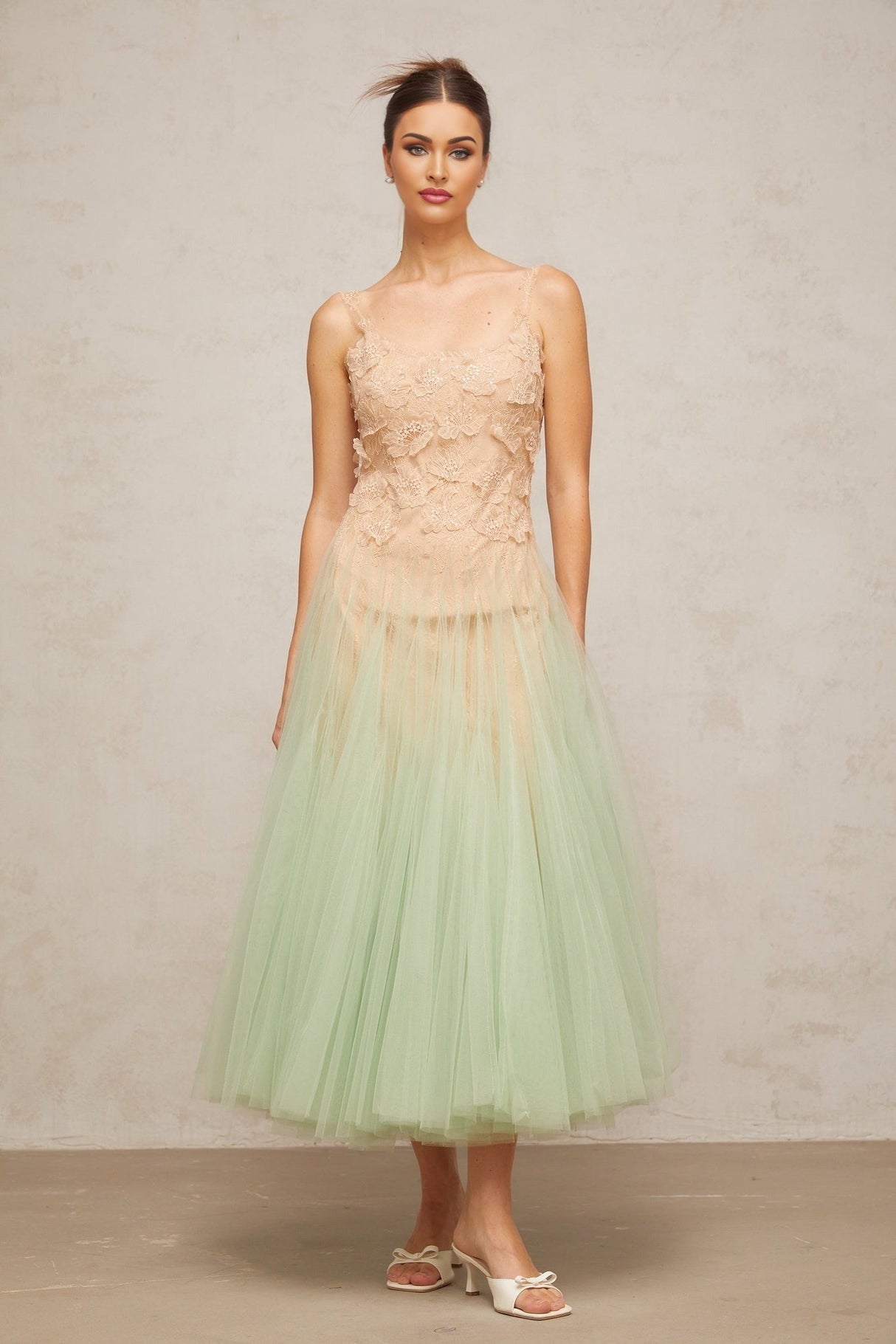 A green midi dress with lace panelling and tulle fabric featuring a feminine silhouette and delicate details