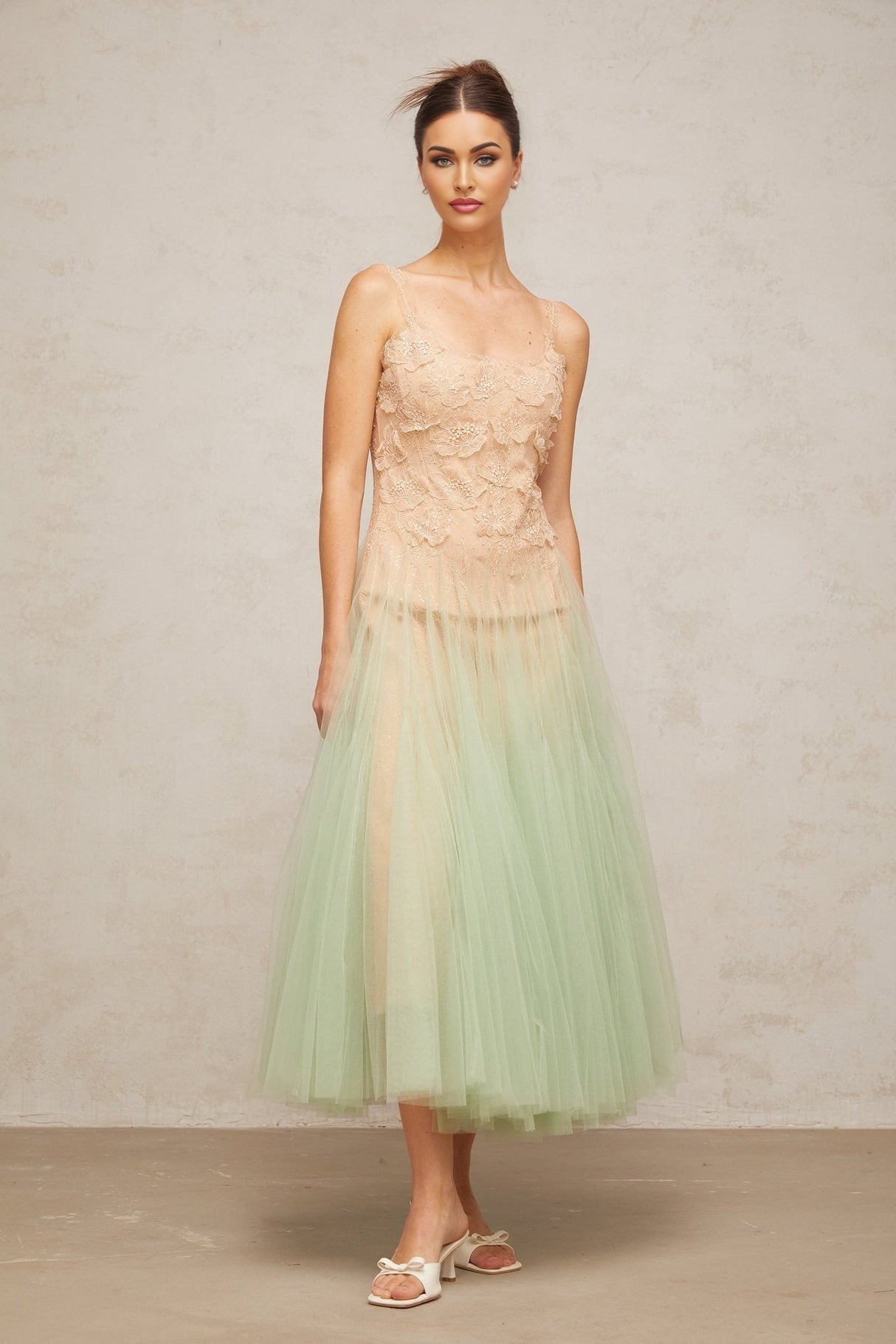 A green midi dress with lace panels and tulle fabric featuring a feminine silhouette and delicate details