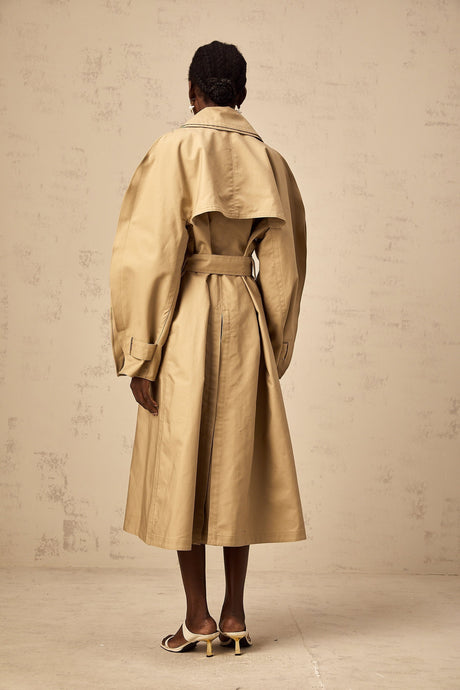 A khaki trench coat with curved sleeves modeled by someone named Jaden or in a style associated with Jaden