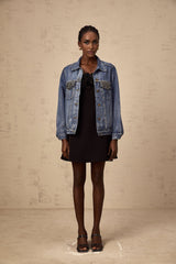 A light blue denim jacket adorned with sparkling rhinestones featuring a classic collar and button front closure