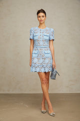 A light blue mini dress with floral lace appliques and ruffled details featuring a fitted bodice and short flared skirt