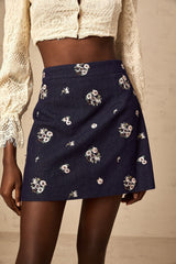 A light blue mini skirt with delicate floral embroidery scattered across the fabric featuring a high waistline and a short hemline
