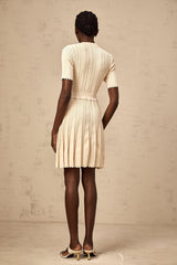 A lightcolored mini dress with a pleated knit design and delicate pointelle trim details along the edges