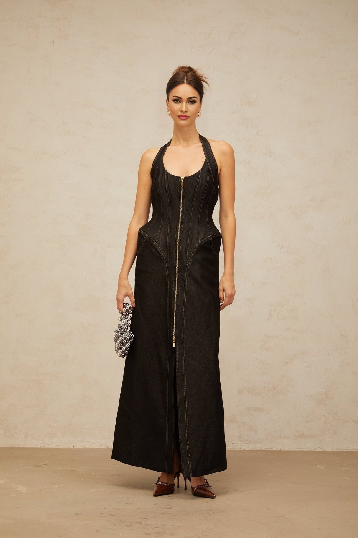 A long black denim maxi dress with a front slit and contrasting stitching details worn by a model named Adrienne