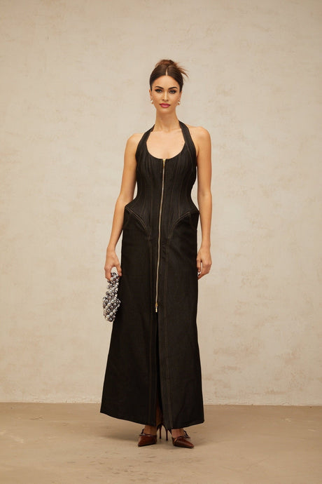 A long black denim maxi dress with a front slit and contrasting stitching details worn by a model named Adrienne