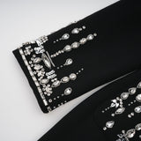 A long black maxi dress with a blazer style top featuring embellishments and a cinched waist