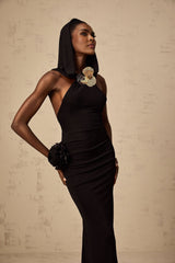 A long black maxi dress with a hood featuring floral appliques worn by a model standing against a plain background