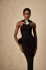 A long black maxi dress with a hood featuring floral appliques worn by a model standing against a plain background