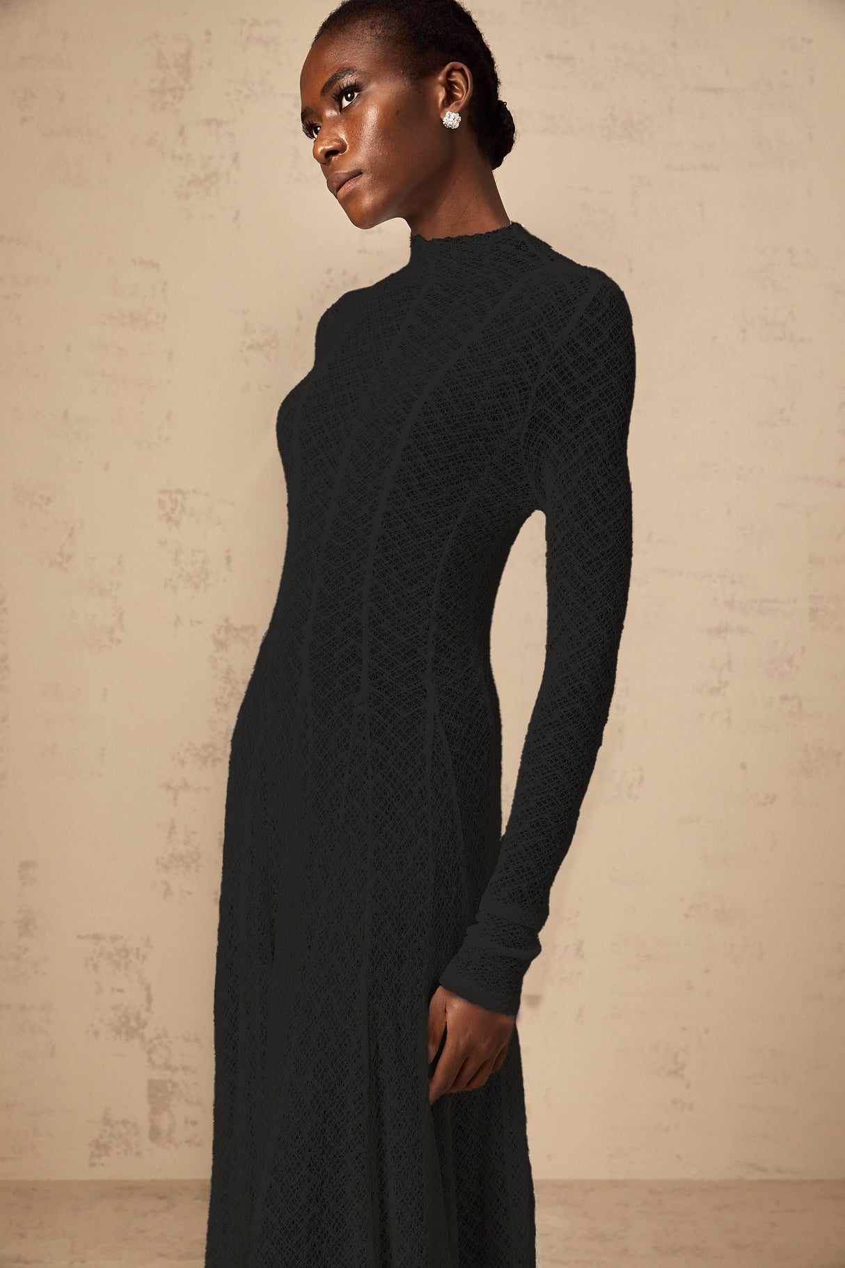 A long black maxi dress with a wavy lace pattern covering the entire garment called the Athena dress