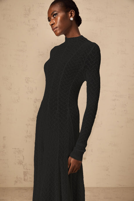 A long black maxi dress with a wavy lace pattern covering the entire garment called the Athena dress