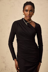 A long black maxi dress with an asymmetric hemline featuring tulle fabric and cutout details worn by a model standing against a plain background