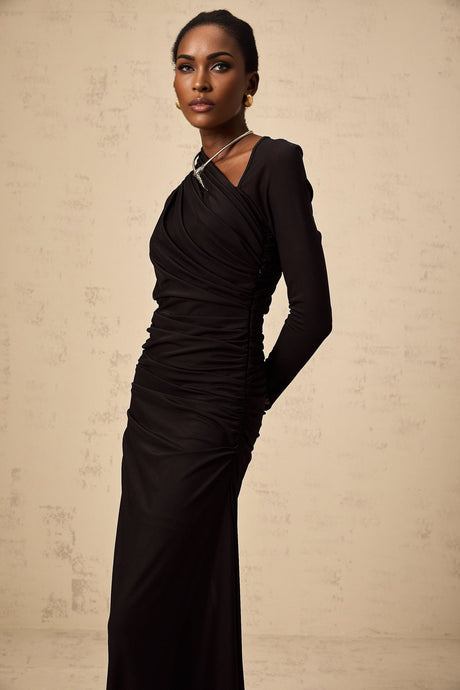 A long black maxi dress with an asymmetric hemline featuring tulle fabric and strategic cutouts on a model named Natalie