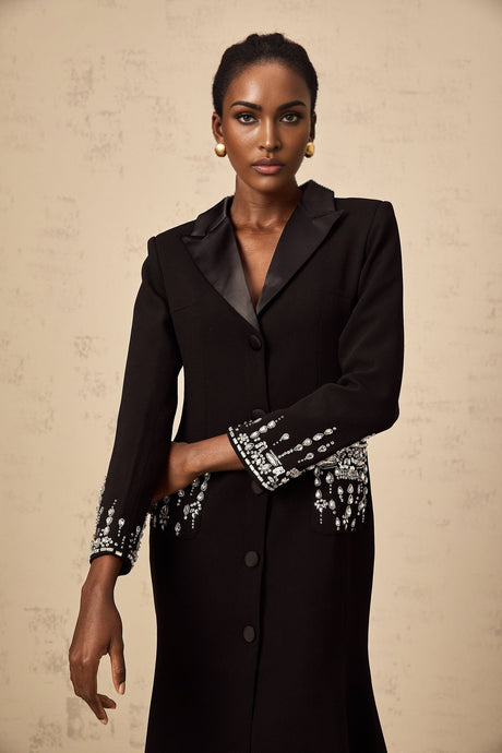 A long black maxi dress with blazer style top embellished with decorative details and featuring a feminine silhouette