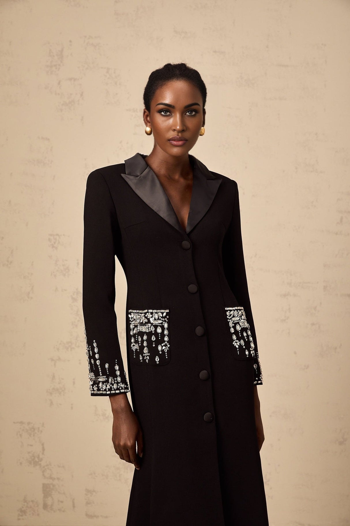 A long black maxi dress with blazer style top featuring embellishments worn by a model