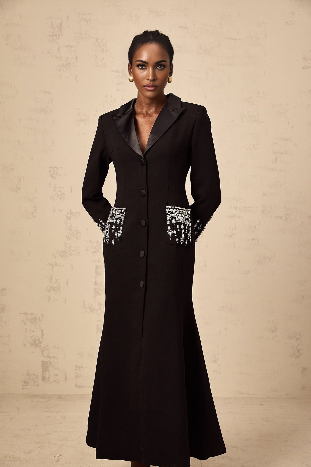 A long black maxi dress with blazer styling featuring embellished details and a feminine silhouette