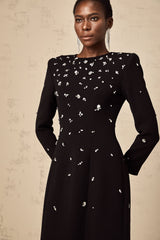 A long black maxi dress with crystal embellishments on the fabric sparkling against the dark background
