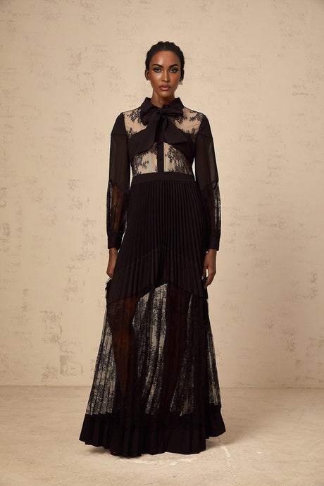 A long black maxi dress with pleats and floral lace panels featuring a feminine silhouette and elegant design
